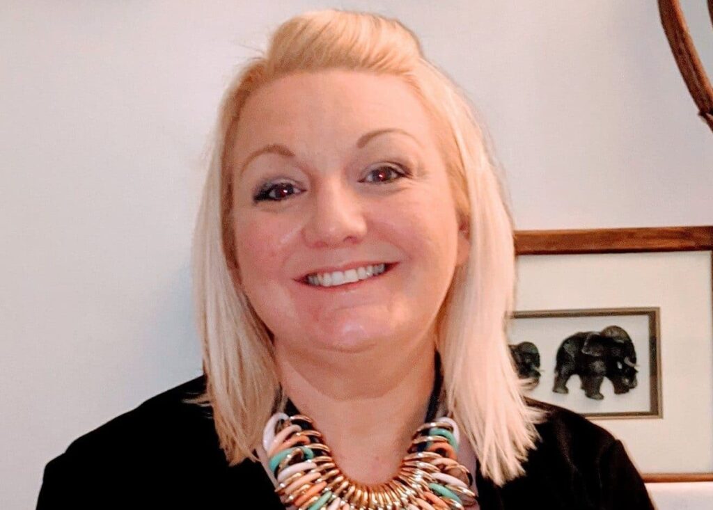 A headshot of Sarah Vaughn, Director of Operations. She has blonde hair and is smiling