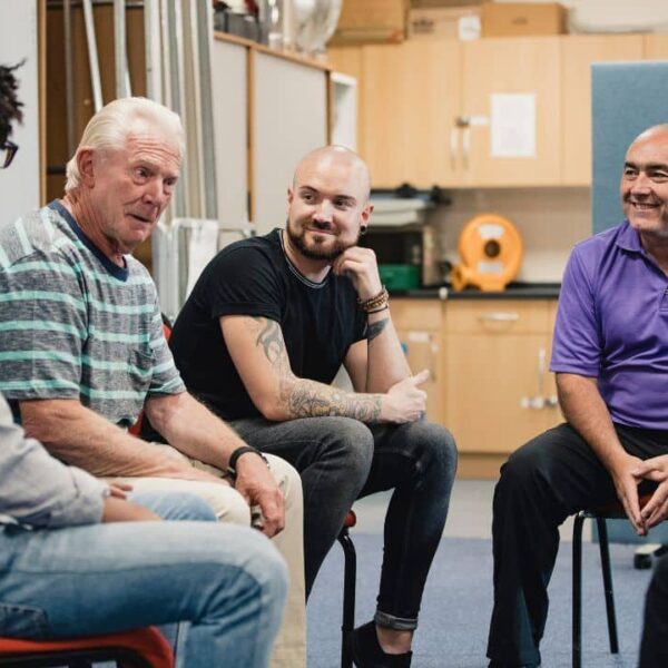 A group of men sitting in a discussion group, providing support to one another.