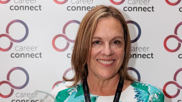 Senior Careers Adviser Jenny Booth holding her award from Career Connect in front of a banner that has the old Career Connect logo on.