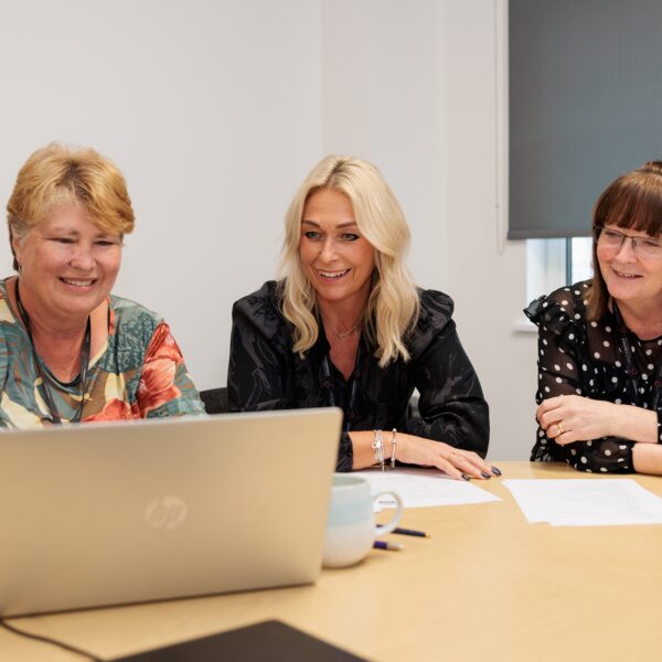 Members of Career Connect's training team delivering a course. Three women are at a desk, with a laptop in front of them.