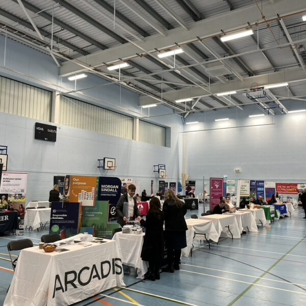 A sports hall with lots of stalls set up for a careers fair.