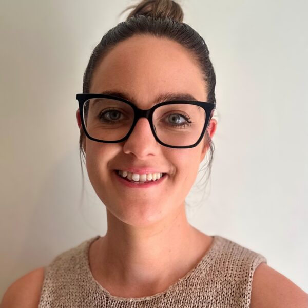 A head and shoulders photo of Alicia. She is wearing glasses, as her dark hair in a bun, and is smiling.
