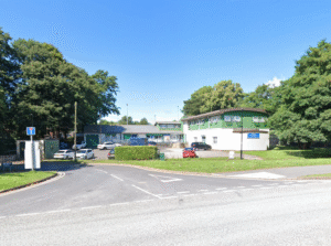 an image of a green and white building by a junction on a sunny day