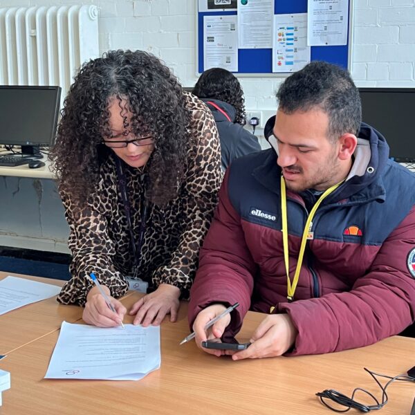 A female Career Connect adviser is helping a young man fill in a form.