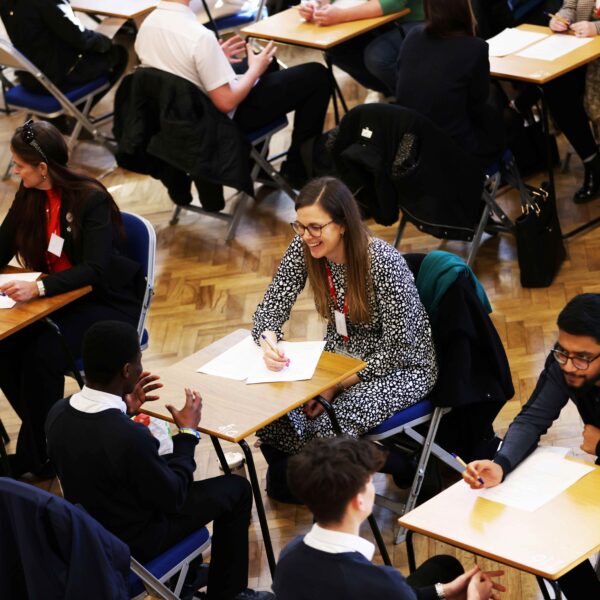 A school hall set up with mock interviews taking place. The image focuses on a female employer and a student in conversation.