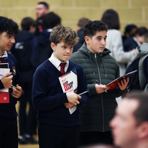 three male students holding booklets that say "get future ready" whilst at a careers fair