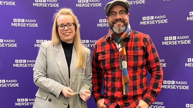 Katie Enstone with her ERSA award next to BBC Radio Merseyside presenter in front of a banner with the BBC Radio Merseyside logo on