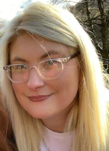 Head and shoulders photo of Katie Haynes. Katie is smiling and wears glasses.