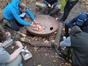 A team instructors showing young people how to safely light a fire in a special metal brazier.