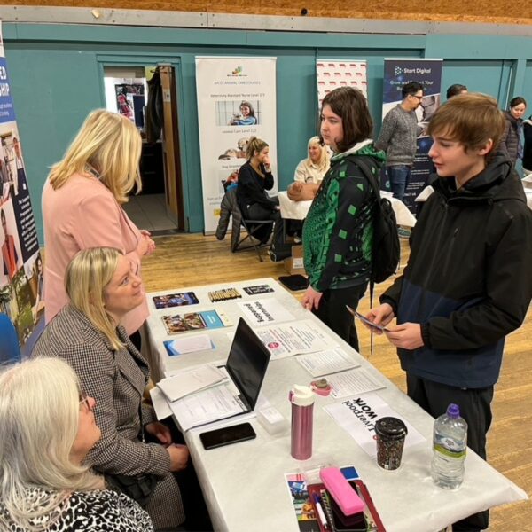 Two young men speak to careers advisers at Liverpool Careers Fair.