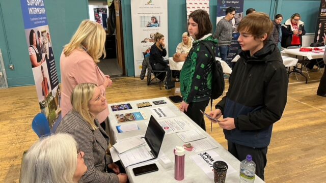 Two young men speak to careers advisers at Liverpool Careers Fair.