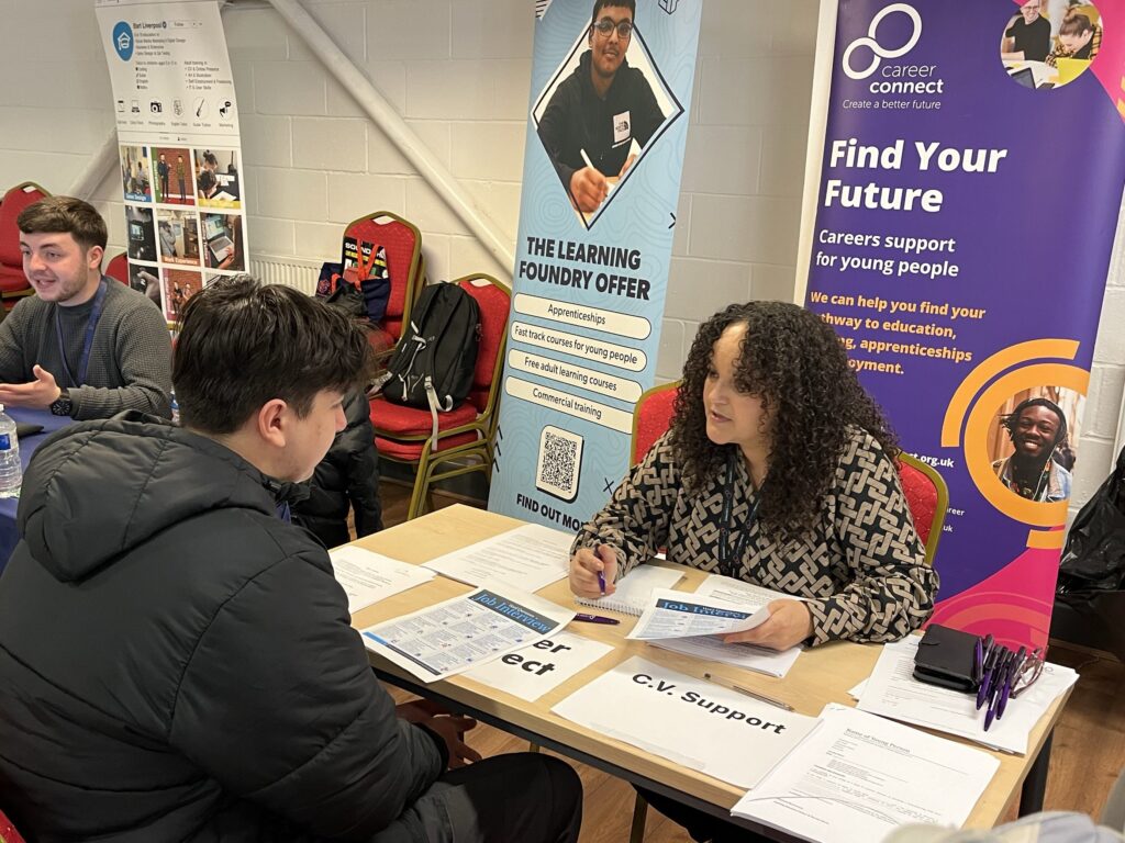 Careers adviser Amnah speaking to a young person over a table at a careers event