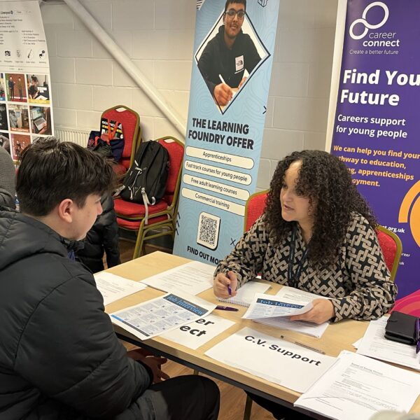 Careers adviser Amnah speaking to a young person over a table at a careers event