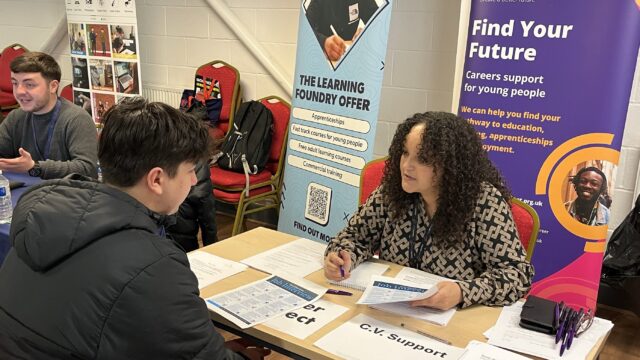 Careers adviser Amnah speaking to a young person over a table at a careers event