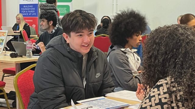 A young person sat at a table receiving careers advice from a career connect adviser at a careers event
