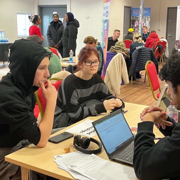 Two young people sat at a table receiving careers advice from a career connect adviser at a careers event