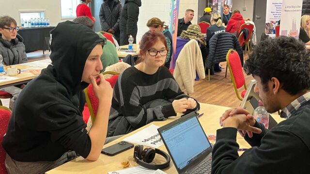 Two young people sat at a table receiving careers advice from a career connect adviser at a careers event