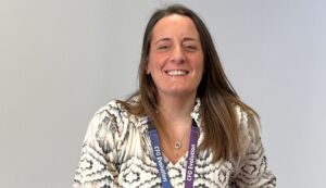 Natalie is a support worker on the CFOE contract. She is sitting in a chair smiling and looking friendly.