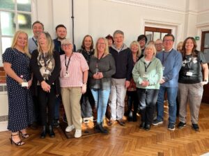 A group shot of the Sefton Career Connect team in their community office. The team are standing up and smiling at the camera.