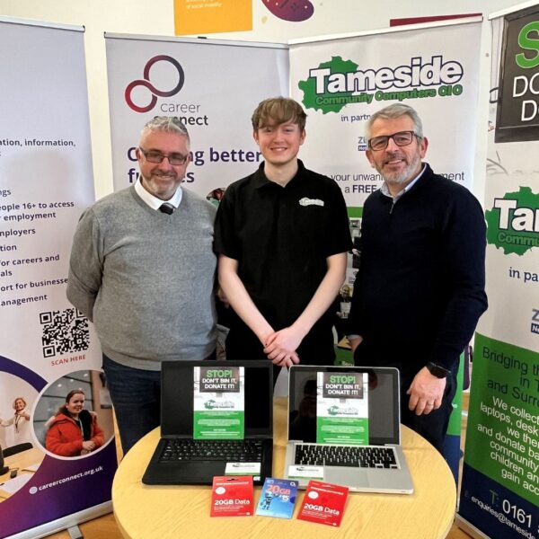 Two Career Connect employees and one Tameside Community Computers employee stood smiling in front of two pull up banners from each company
