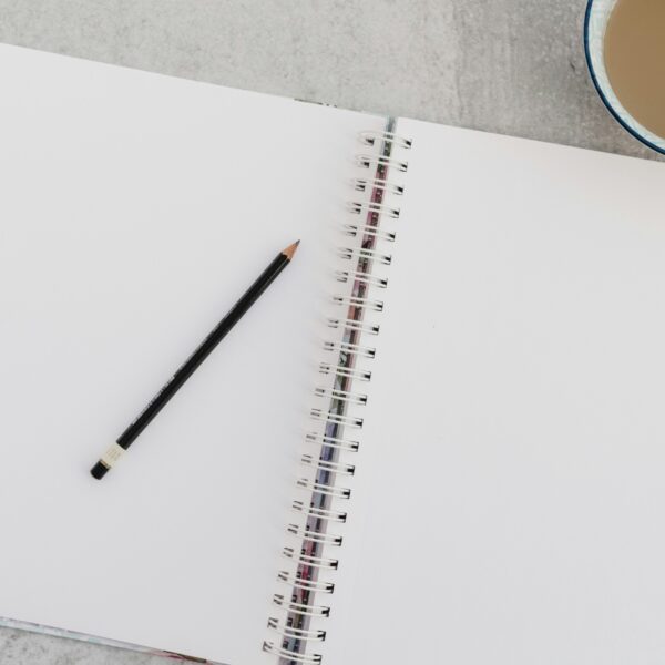 an open, clean spiral bound notebook, with a pencil on the left hand page.
