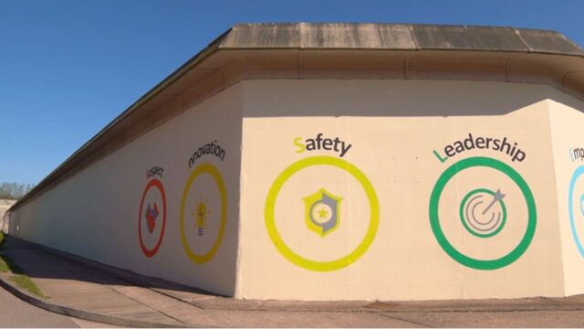 An outbuilding at a prison. It has a motivational mural on the side, with the words in different coloured circles: respect, innovation, safety, leadership and empathy.