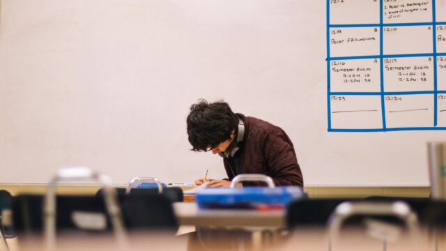 A student sat in an empty classroom engrossed in his studies