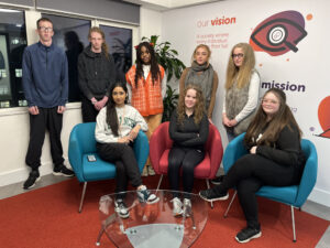A group of Career Connect youth ambassadors sitting and standing in the career connect offices, smiling at the camera.