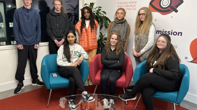 A group of Career Connect youth ambassadors sitting and standing in the career connect offices, smiling at the camera.