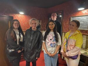 A group of five Youth Ambassadors in an escape room as part of their enrichment activities. They are all smiling at the camera.