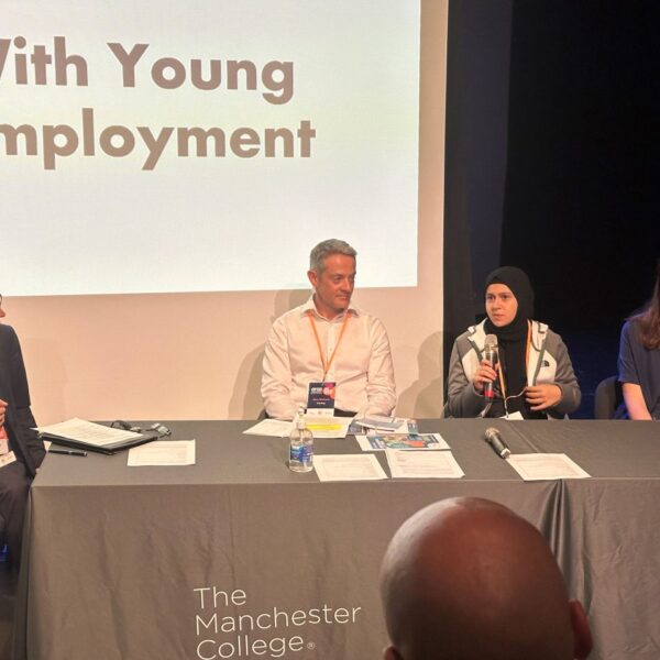 Youth ambassador Yasmina sat on a panel speaking into a microphone