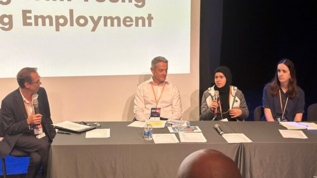 Youth ambassador Yasmina sat on a panel speaking into a microphone