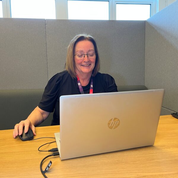 A female careers adviser in an online careers advice session with a client. She is smiling and looking at the laptop.