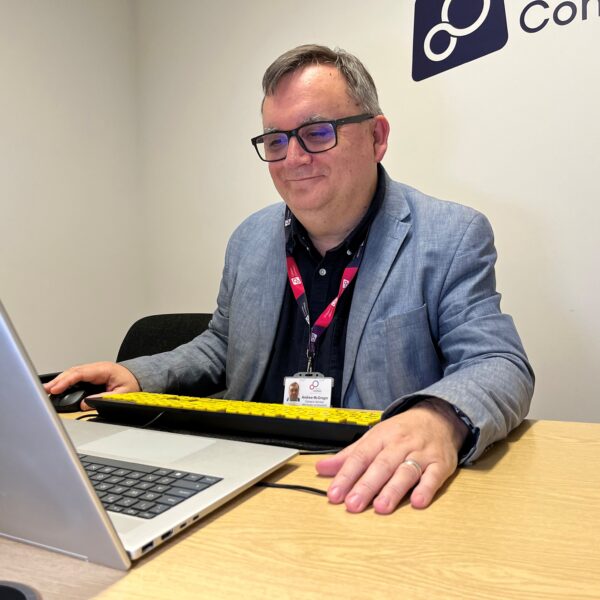 A male Career Connect adviser at his computer talking to a client in a careers interview. He is smiling and interacting.