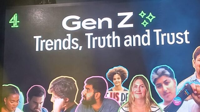 A male speaker - Joe Hall, Senior Research Executive at Channel 4 - is on stage at the Raise Up Event, holding a microphone and speaking. Behind him is a screen with images of young people and the words 'Gen Z - Trends, Truth and Trust'
