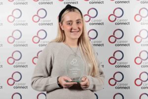 Kasey Lee holding an award she won at the ConnectUs staff awards. Kasey is holding a trophy inscribed with her name and the words Professional award.