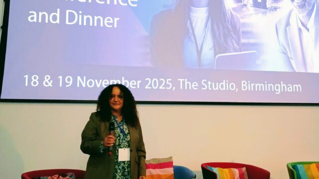 A woman standing in front of a CDI national conference and dinner presentation