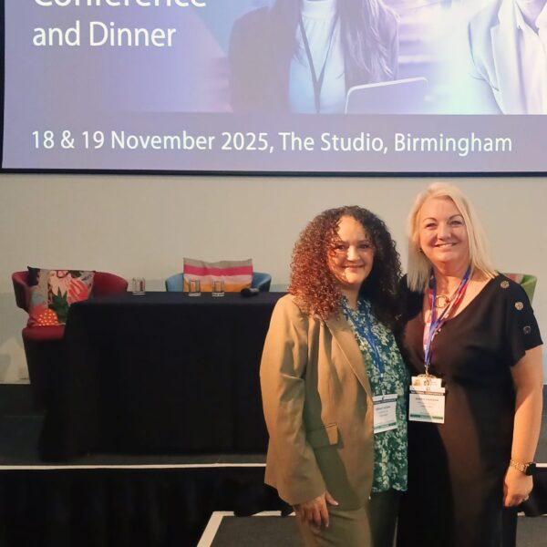 Two women standing in front of a CDI national conference and dinner presentation