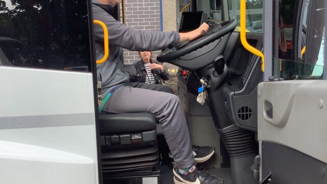 A male youth behind the steering wheel of a bus during a careers event.