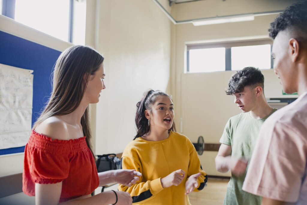 A group of young people talking together in a white room.