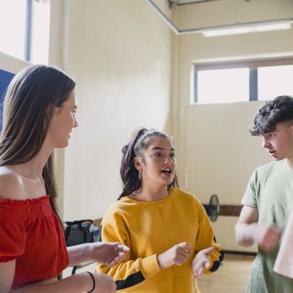 A group of young people talking together in a white room.