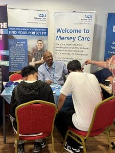 An image of young people talking to representatives from Mersey Care NHS Trust at Liverpool Career Fest.