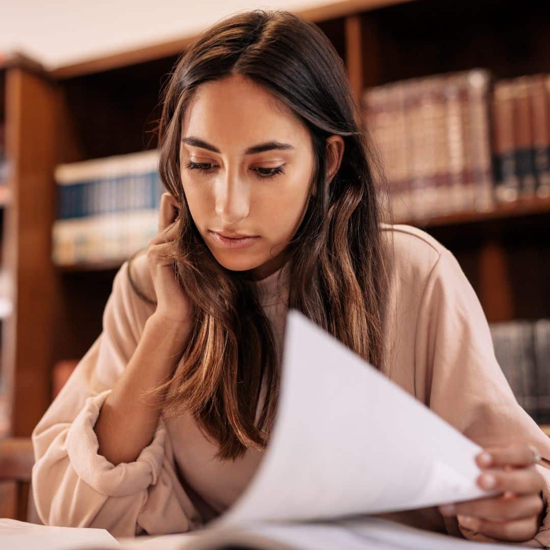 A young woman studying a book in a library.