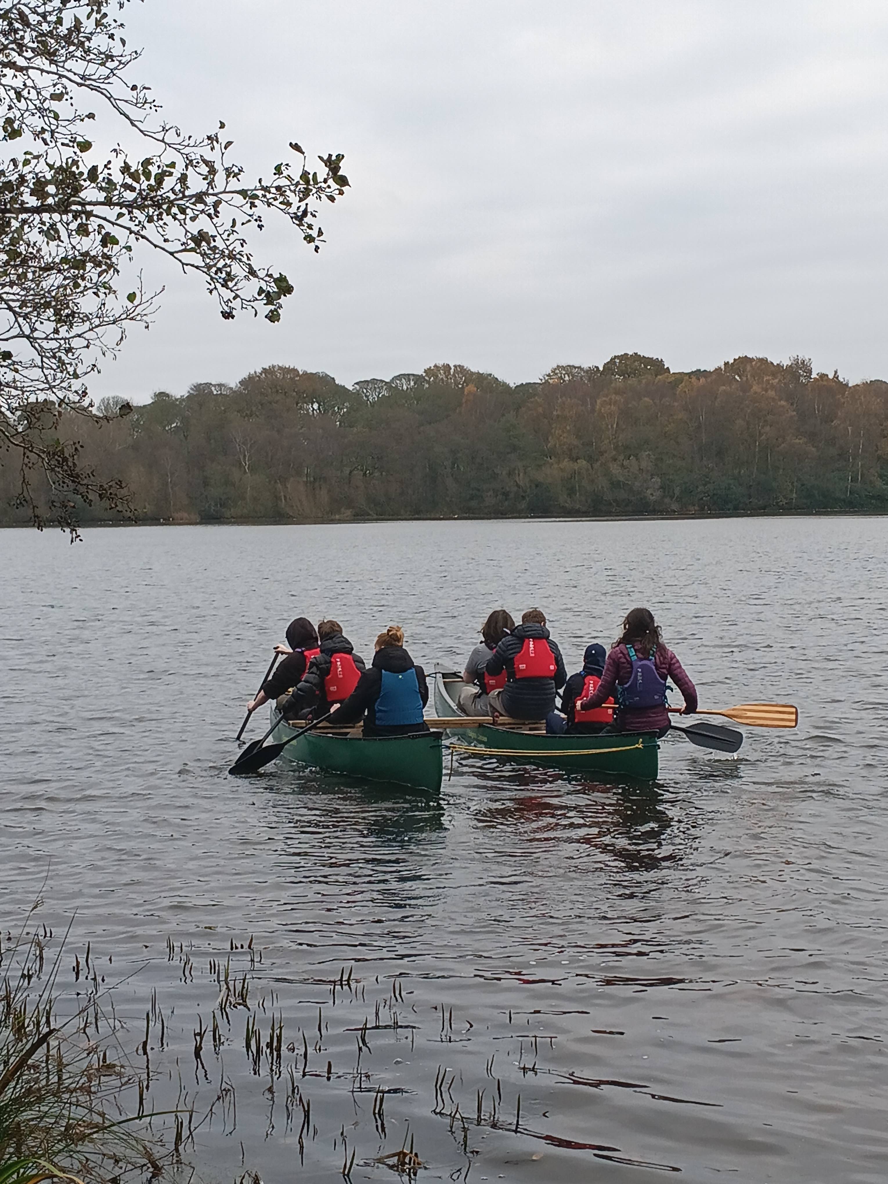 A group of people paddling a canoe across a lake.