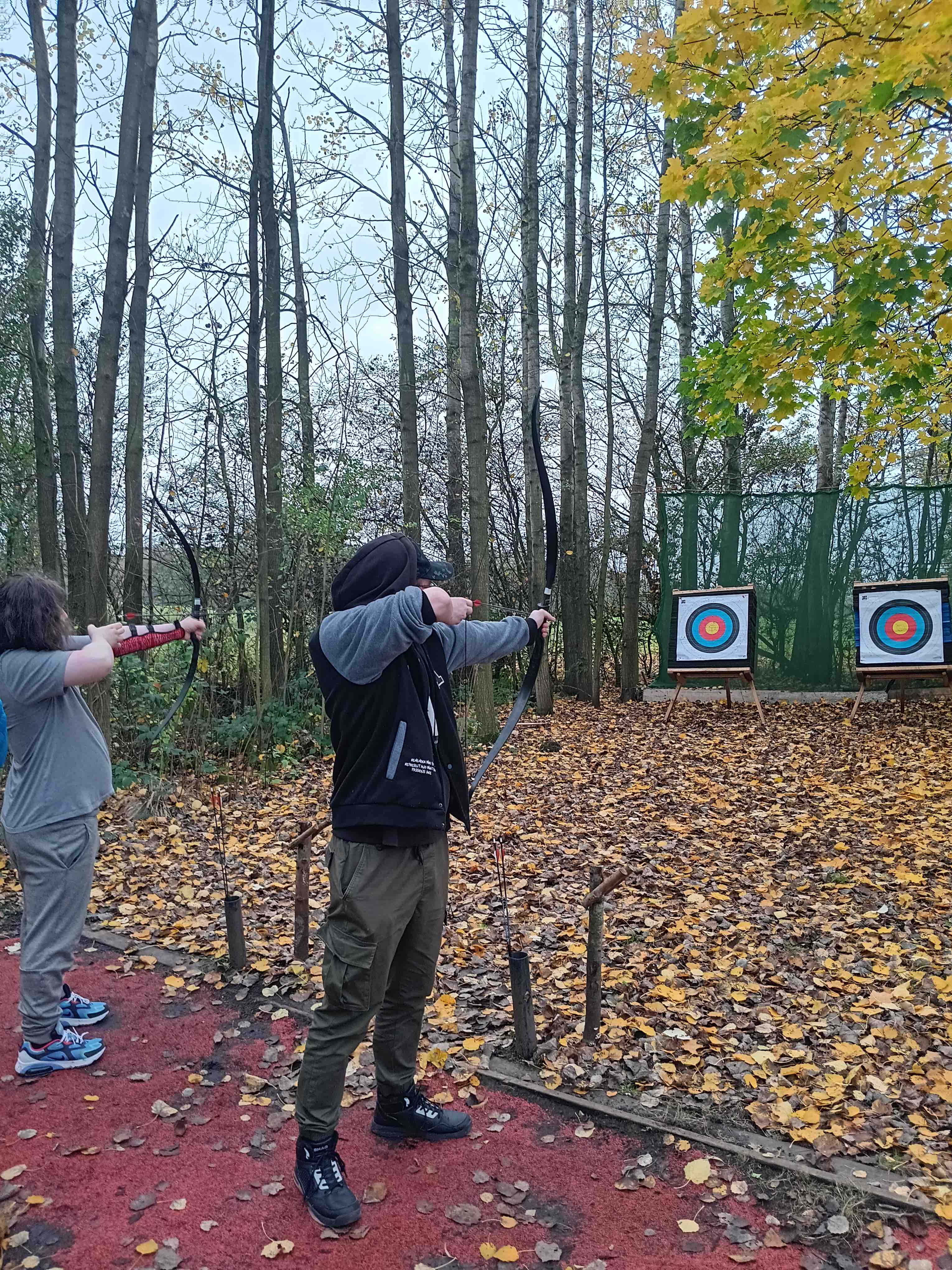 Some young people practising archery in the woods.