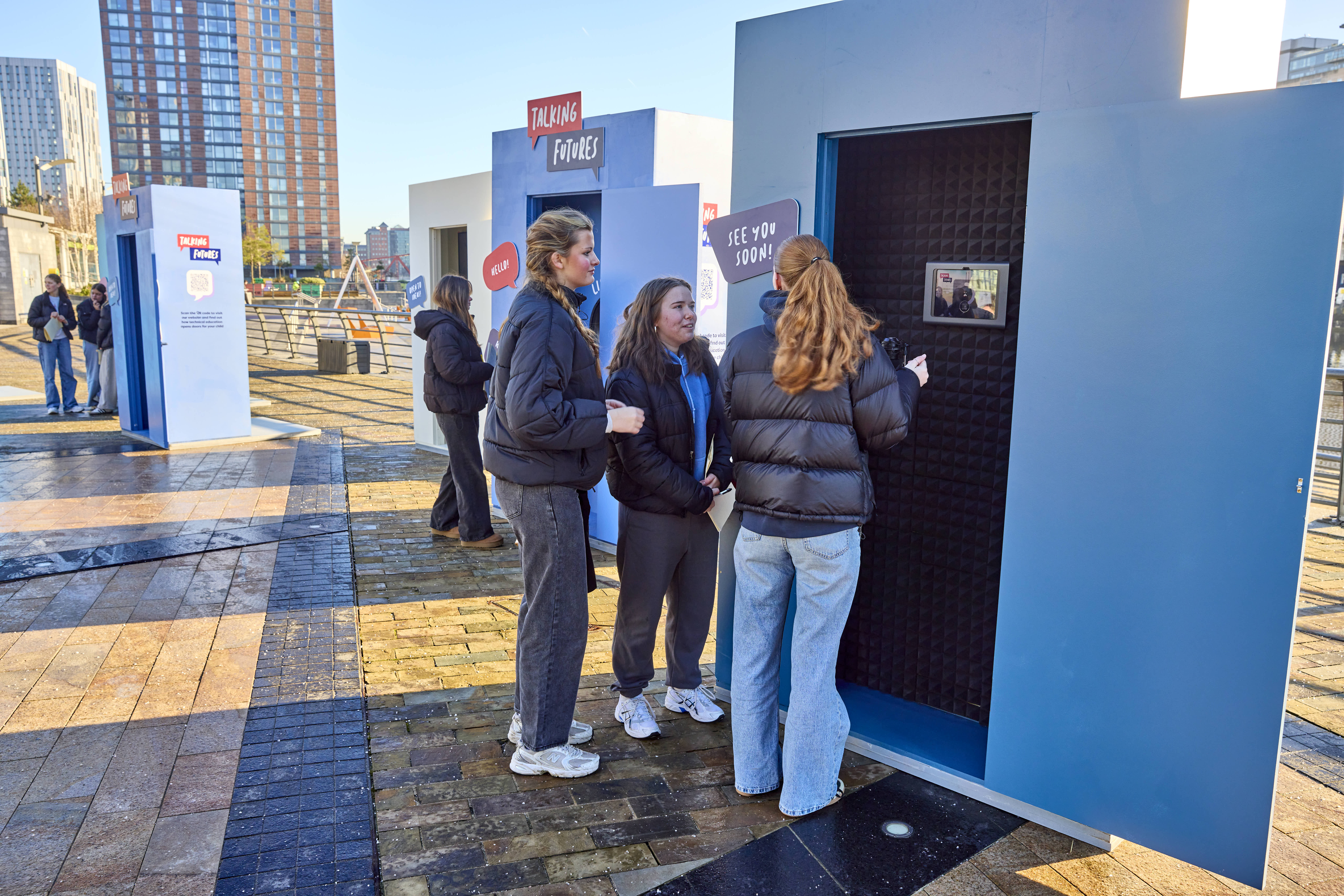 A group of people trying out one of the Talking Future information booths that allows them to see and speak to a careers adviser via a video screen.